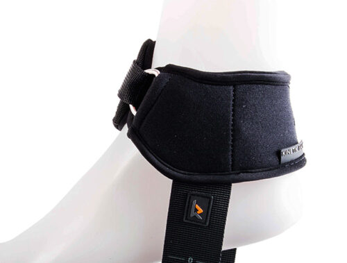 Czarna neoprenowa orteza na kostkę z regulowanym paskiem zapinanym na metalową klamrę i pionowym pasem z małym logo, umieszczona na białej manekinowej stopie.