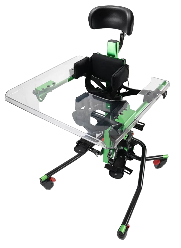 Stojak rehabilitacyjny (stander) z zielono‑czarną metalową ramą, regulowanym przezroczystym blatem, miękkim czarnym oparciem i podgłówkiem oraz pasami podtrzymującymi, osadzony na czterech kółkach.