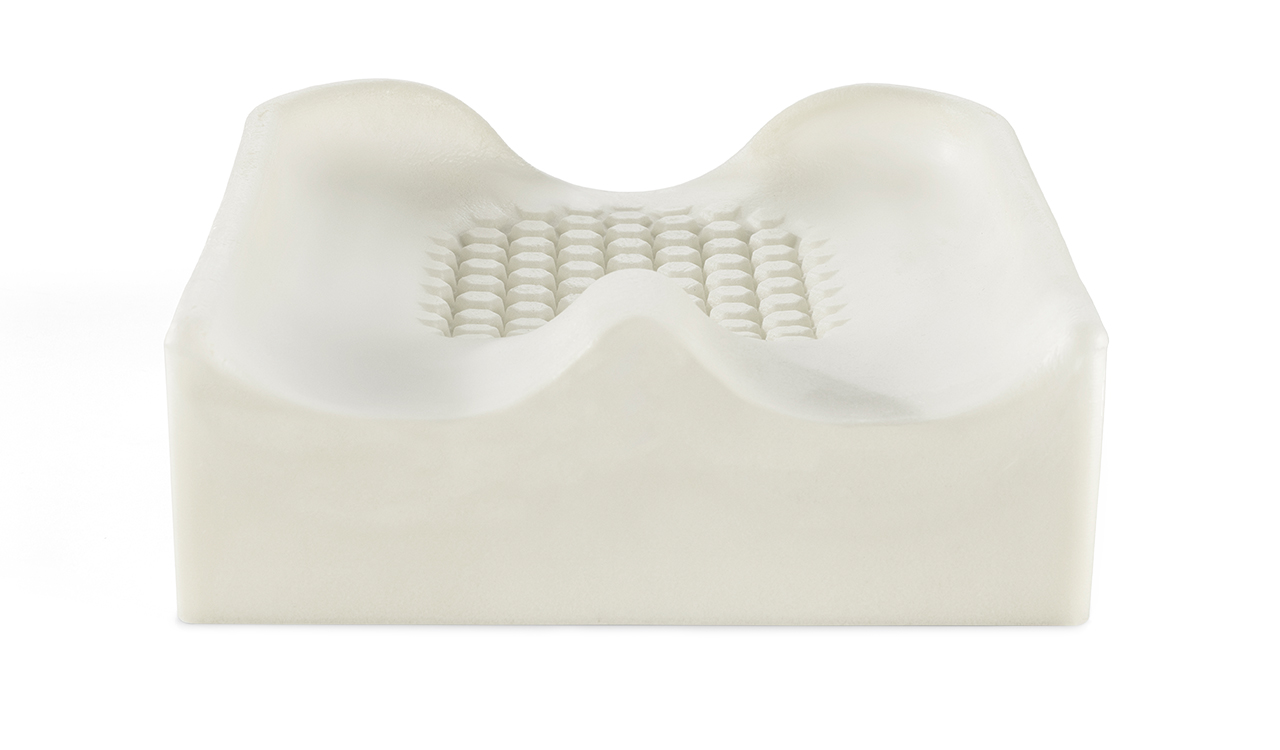 Biała profilowana piankowa poduszka z dwoma bocznymi wgłębieniami i centralnym polem z regularnymi wypukłymi oczkami.