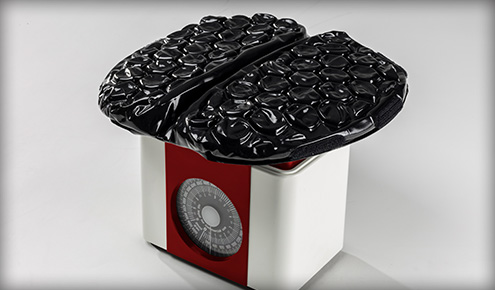 Biała waga kuchenna z czerwoną tarczą i srebrnym cyferblatem, na górze dwie połowy czarnej, błyszczącej powierzchni z bąbelków.