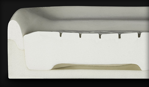 Przekrój piankowego materaca ukazujący warstwy, pionowe nacięcia wentylacyjne i pustkę podporową u podstawy.