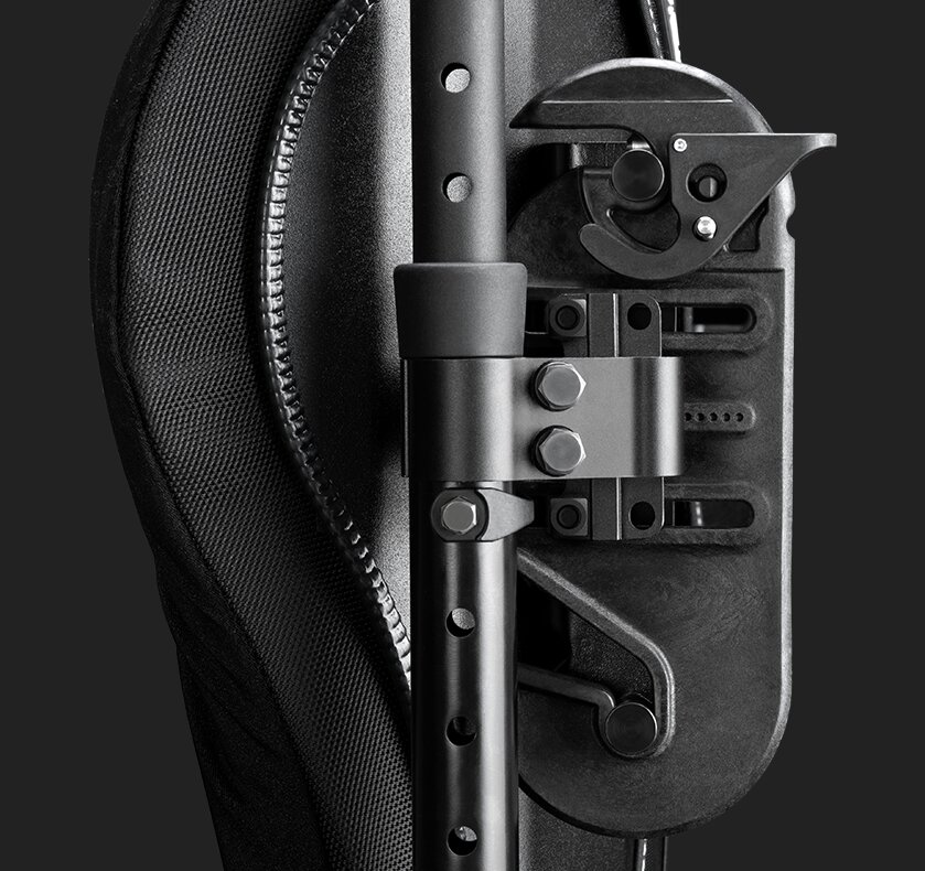 Zbliżenie mechanizmu regulacji oparcia krzesła: pionowy trzpień z otworami, zacisk ze śrubami i teksturowana tapicerka.